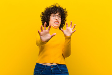 young pretty afro woman feeling terrified, backing off and screaming in horror and panic, reacting...