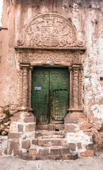 Entrance door of a clay house with decoration in relief on a street of Juli city, Puno region, Peru