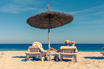Happy European couple laying on sunbeds under straw umbrella at the tropic beach. They enjoying their vacations. - 300431037