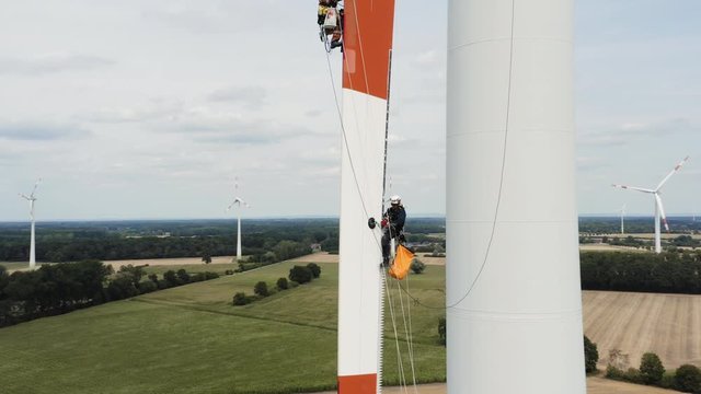 People suspended securely high in air on windmill working, aerial