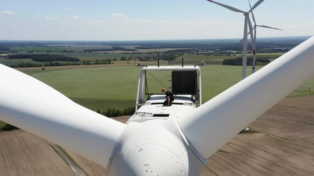 Person working on the windmill , turbine high above on top, aerial