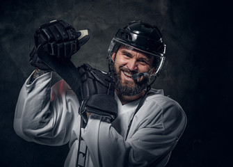 Happy cheerful hockey player has a photo session at dark photo studio. © Fxquadro