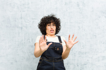 young pretty afro woman feeling terrified, backing off and screaming in horror and panic, reacting...