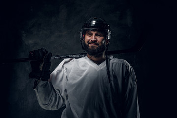 Fototapeta na wymiar Confident emotional hockey player with hockey stick is posing for photographer.