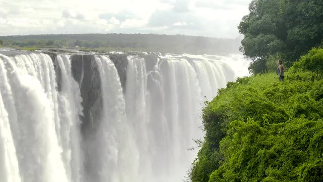 Woman overlooking Victoria Falls waterfall wide angle