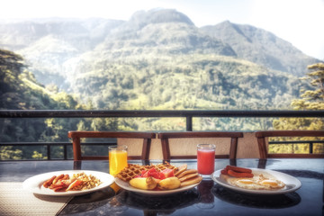 Breakfast in restaurant with beautiful view on mountains range in summer sunny morning during travel holidays