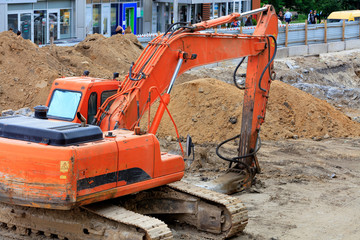 Heavy construction excavator crawler bucket digs a trench during a collector repair on a city...
