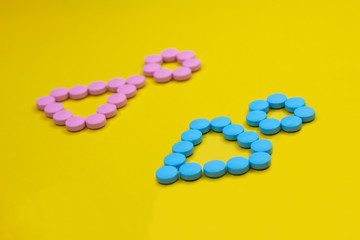 male and female symbols made from pink and blue pills on yellow background.