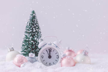 Pink and White glass Christmas balls with an alarm clock on a snowflake background, toned
