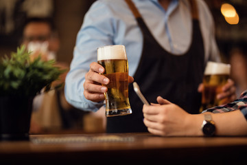 Close-up of waiter serving a beer to his customer in a bar.