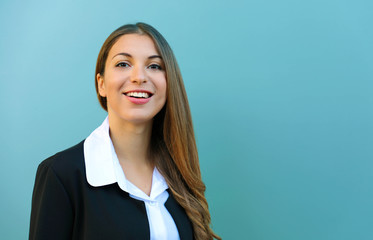 Smiling young business woman with suit standing against blue background outdoor. Copy space.