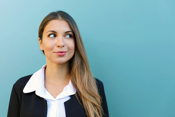 Portrait of business woman standing against blue background looking to the side. Copy space.