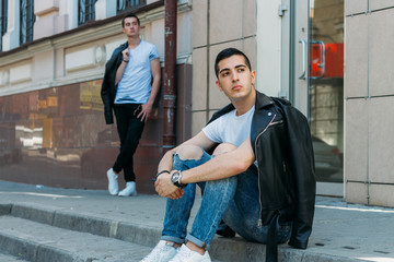 beautiful and attractive guy is standing in the city, posing. walk around the city in black glasses. communication. meeting friends.