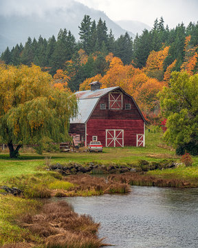 Red barn with fall trees and a pond