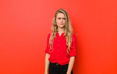 young blonde woman feeling sad, upset or angry and looking to the side with a negative attitude,...