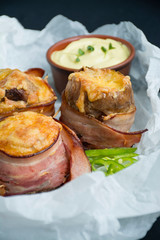 Baked young potatoes with cheese, bacon. Dark background. Close-up.