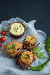 Baked young potatoes with cheese, bacon. Dark background. Close-up. Space for text.