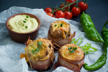 Baked young potatoes with cheese, bacon. Dark background. Close-up.