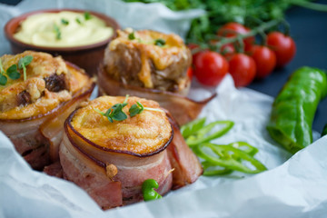 Baked young potatoes with cheese, bacon. Dark background. Close-up.