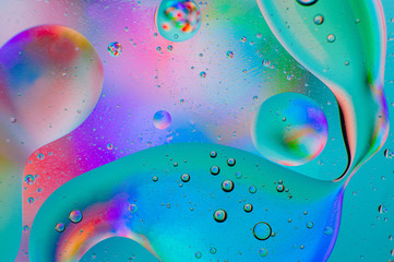 Neon turquoise rainbow abstract macro background of moving oil drops