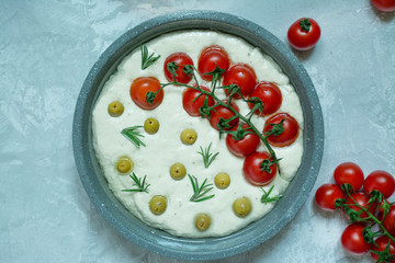 Traditional italian focaccia with tomatoes, olives and rosemary. The process of making focaccia. Italian Cuisine . Space for text.