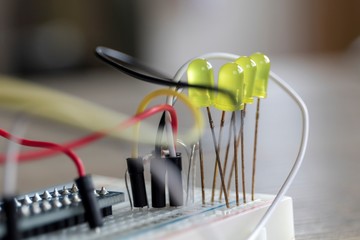 A portrait of a some electronics, it is a bread board with some LED's attached onto it, with some...