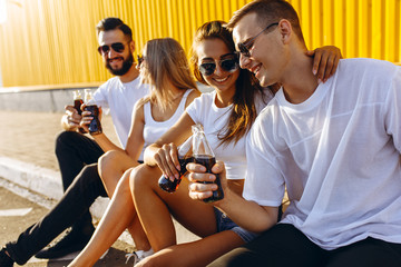 A group of young friends hang out in the city sitting on the asphalt at the yellow wall