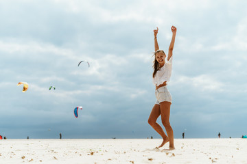 bather dancing on the beach against the background of flying kites