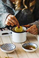 Pouring tea into a cup. Autumn hot herbal tea with honey, cinnamon and lemon. Top view. Image toned.