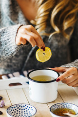 Pouring tea into a cup. Autumn hot herbal tea with honey, cinnamon and lemon. Top view. Image toned.