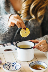 Pouring tea into a cup. Autumn hot herbal tea with honey, cinnamon and lemon. Top view. Image toned.