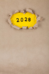 The concept of the New Year with the number 2028 placed in a leaky paper on crumpled yellow paper