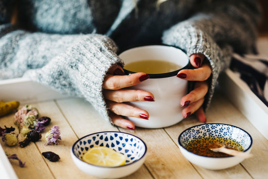 A female model is drinking herbal tea for flu, she is pouring herbal tea into a white enamel cup