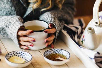 A female model is drinking herbal tea for flu, she is pouring herbal tea into a white enamel cup