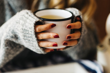 A female model is drinking herbal tea for flu, she is pouring herbal tea into a white enamel cup