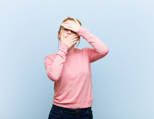 young red head pretty woman covering face with both hands saying no to the camera! refusing...