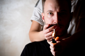 a woman stands behind a man and lights a cigarette