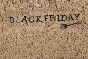 The concept of the inscription Black Friday placed in a sand hole dug with a shovel.