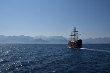 The ship is sailing on the sea. Coast near Antalya, Turkey. On a background of blue sky and mountains