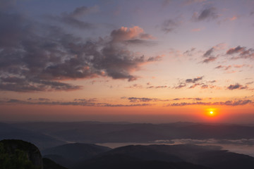View of the sun rising from behind the mountains. Carpathians, Romania