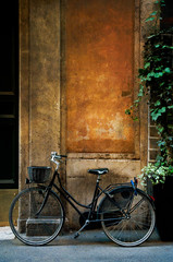Fototapeta na wymiar Old bicycle leaning against an old rustic, weathered wall in Rome, Italy.