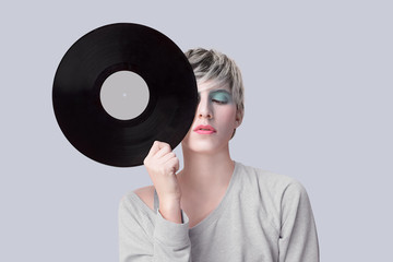 young woman holding vinyl record next to her face