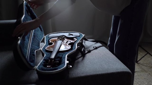 Woman approaches the violin case, opens the case and pulls out his musical instrument close-up in slow motion. Musician is going to start playing the violin