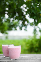 A glass of fresh cold smoothie with berries and cherrys on a wooden table, summer set, outdoor greed blured background,boke.