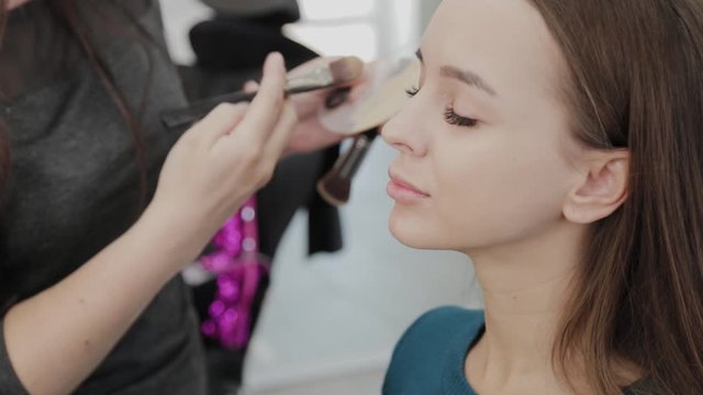 Professional makeup artist woman stirs makeup cream on a palette.