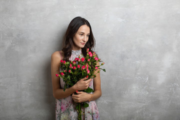 Close-up portrait of attractive young woman in summer dress holding bouquet of roses, girl happy