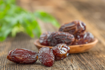 Juicy dates in a bowl on a old wooden table .