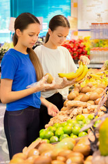 Obraz premium Teen girls shopping in supermarket reading product information. Choosing daily product.Concept of healthy food, bio, vegetarian, diet.
