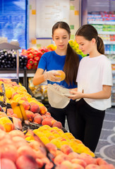 Teen girls shopping in supermarket reading product information. Choosing daily product.Concept of healthy food, bio, vegetarian, diet.