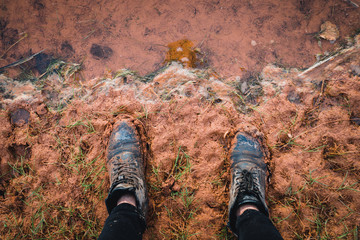 Black leather shoes stuck in clay.